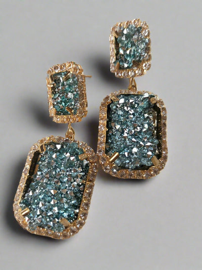 Pair of earrings with blue gemstone-like stones on a white background